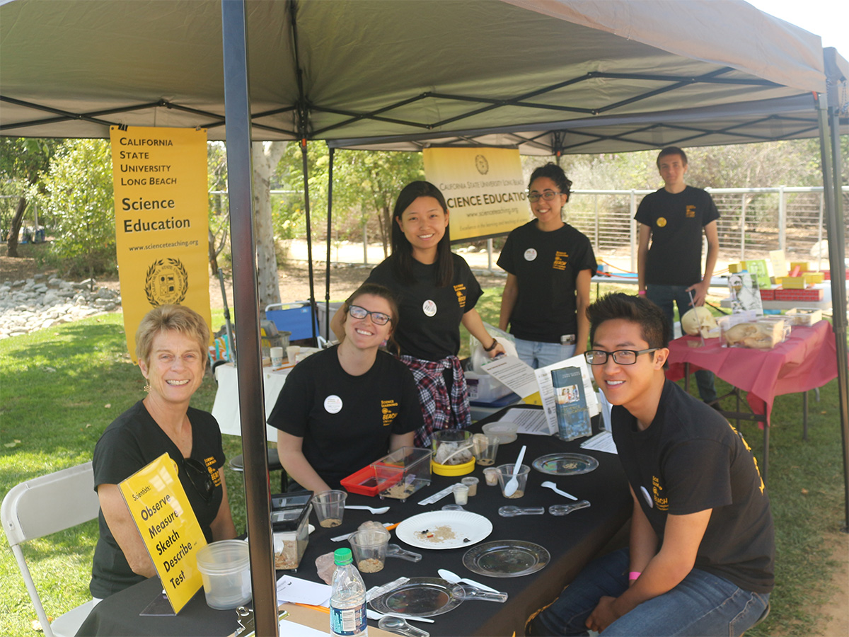 group gathered outside under a tent and smiling