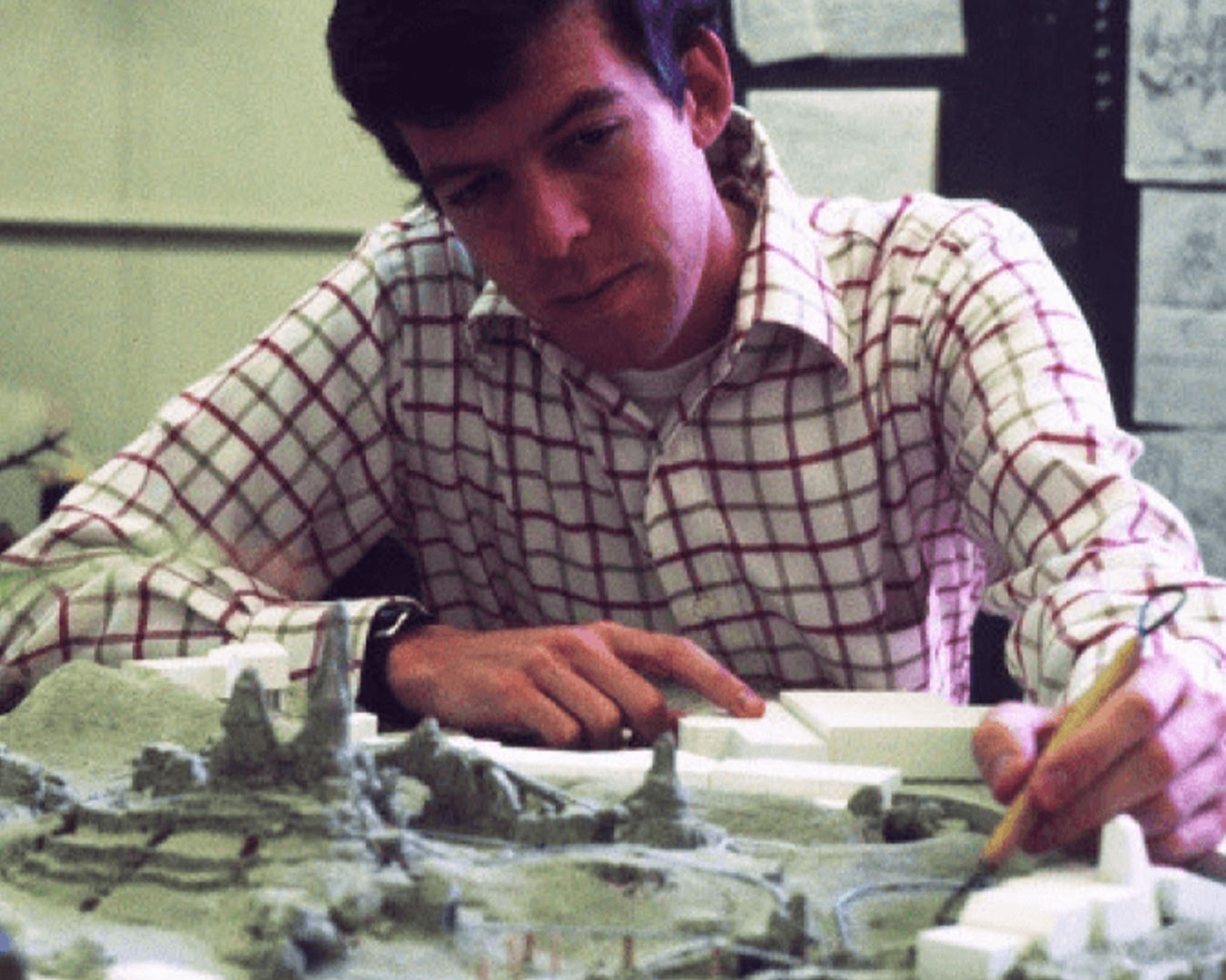 A man uses a putty knife to work on a clay model