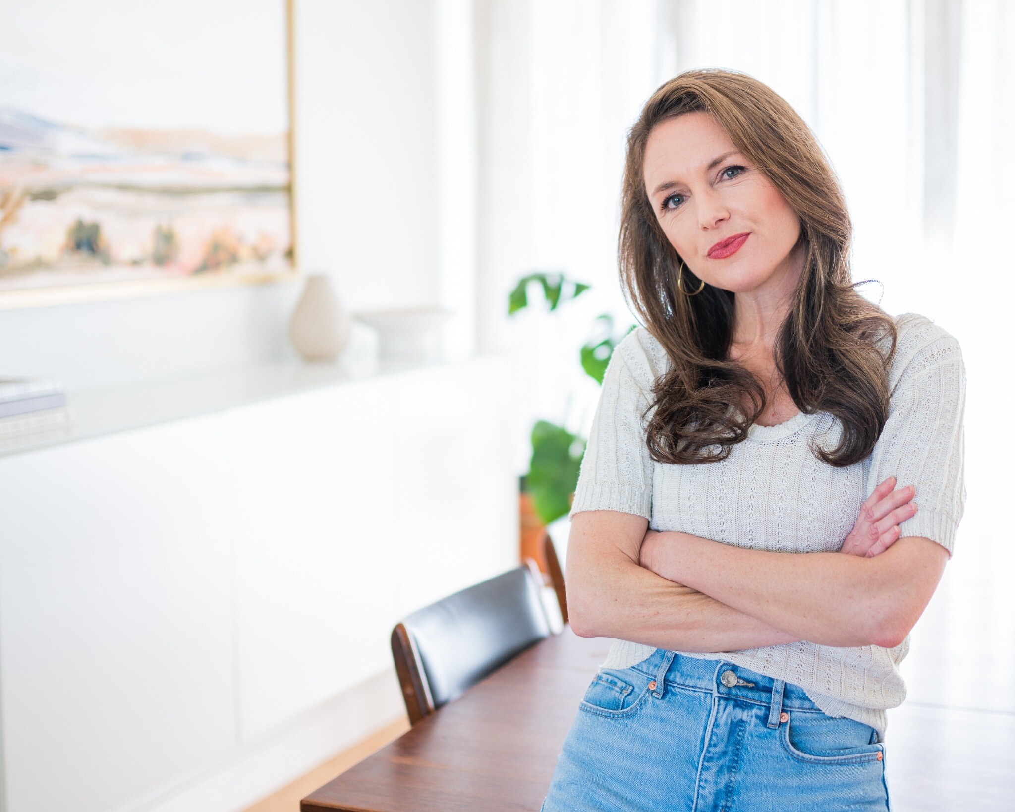 Portrait of Erin Ferry standing with her arms crossed in a bright interior.