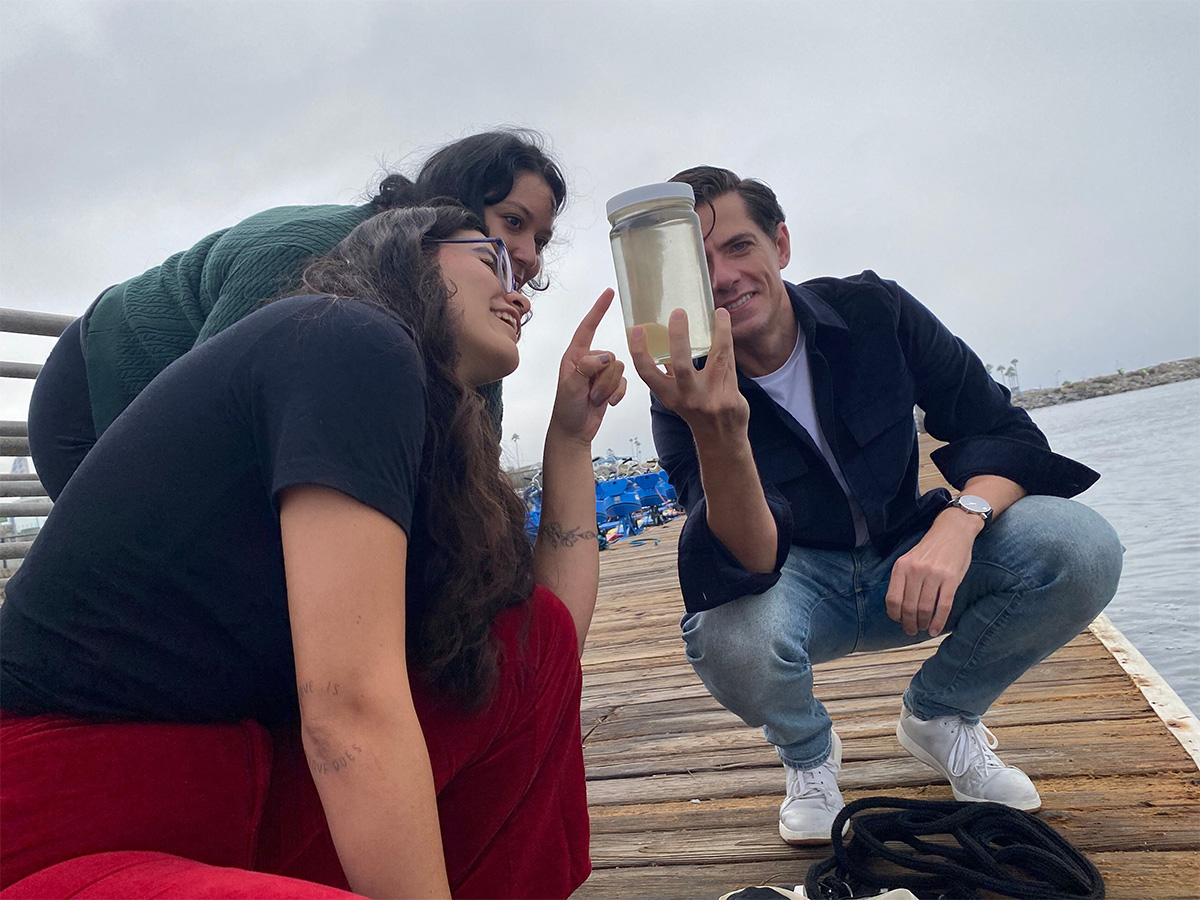 Dr. Michael Carlson holding a sample of seawater in the field as student researchers make observations
