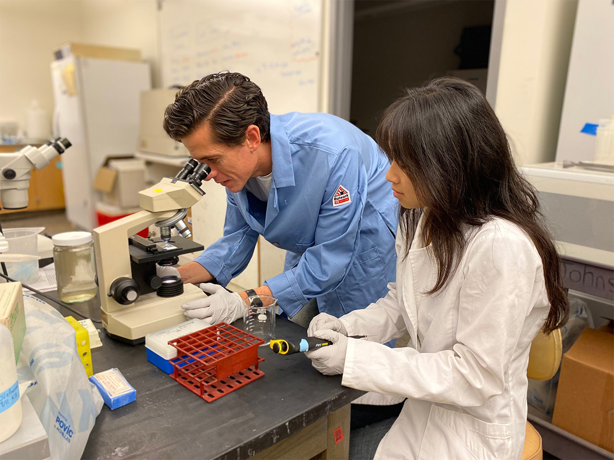 Dr. Michael Carlson and student researcher using a microscope in the lab