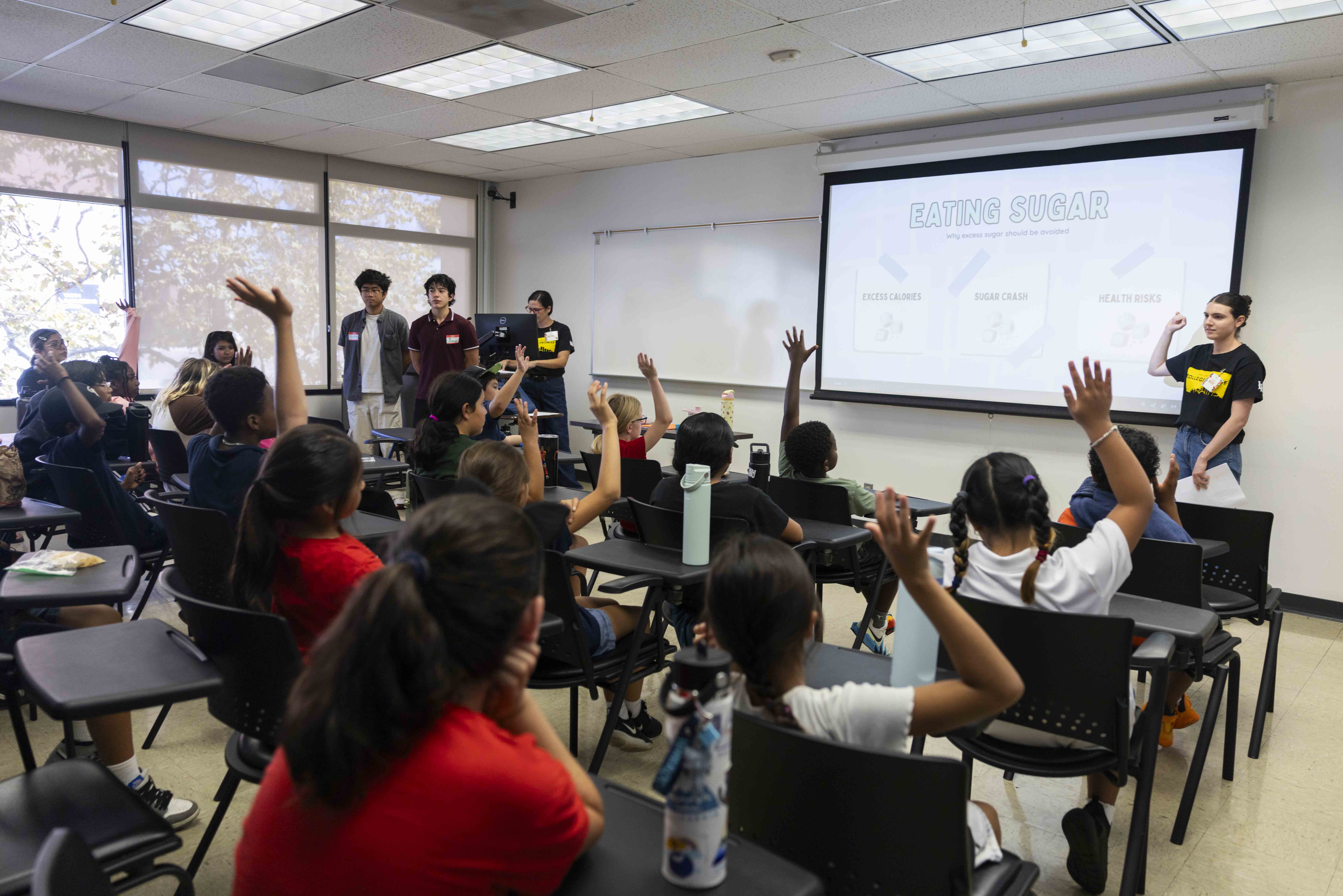 Children raise their hands during a nutrition lesson