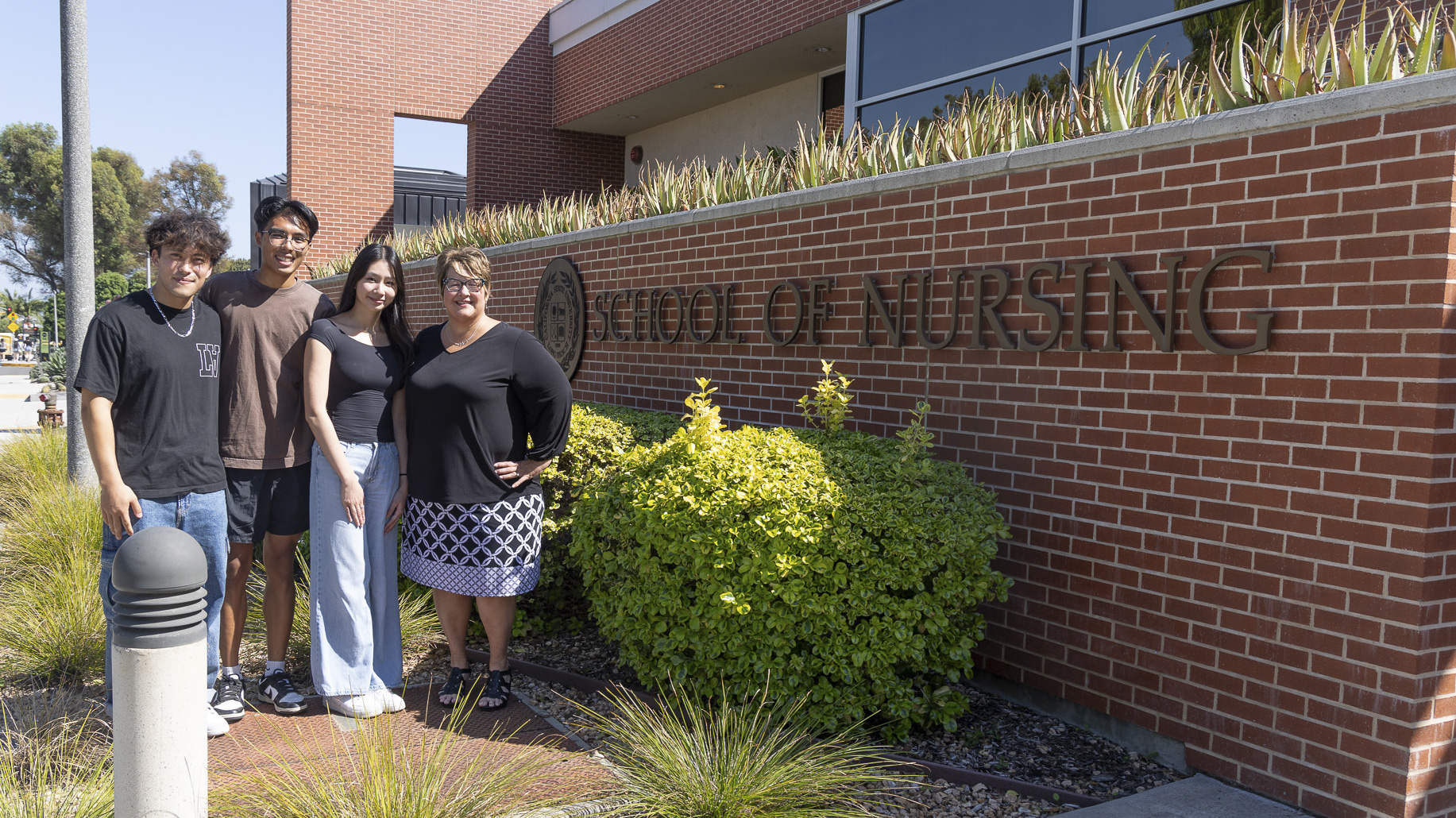 Dr. Beth Manke and three Nursing students stand in front of the School of Nursing building at CSULB