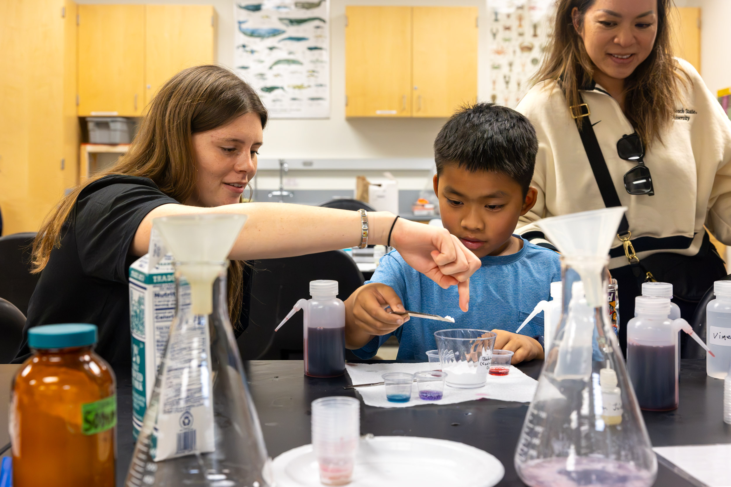 A person guides a child adding powder to a cup.