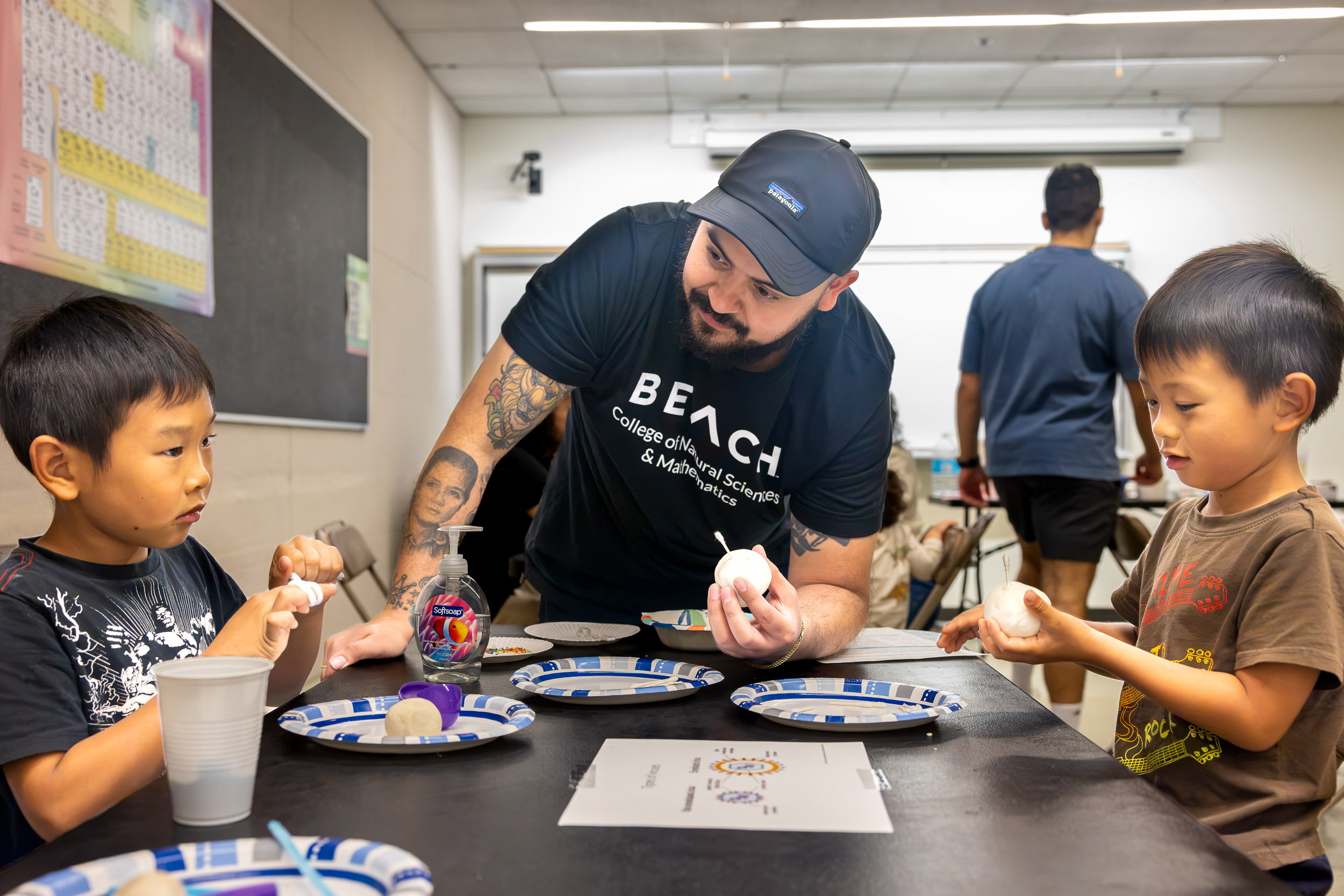 A person helps two children with clay models.