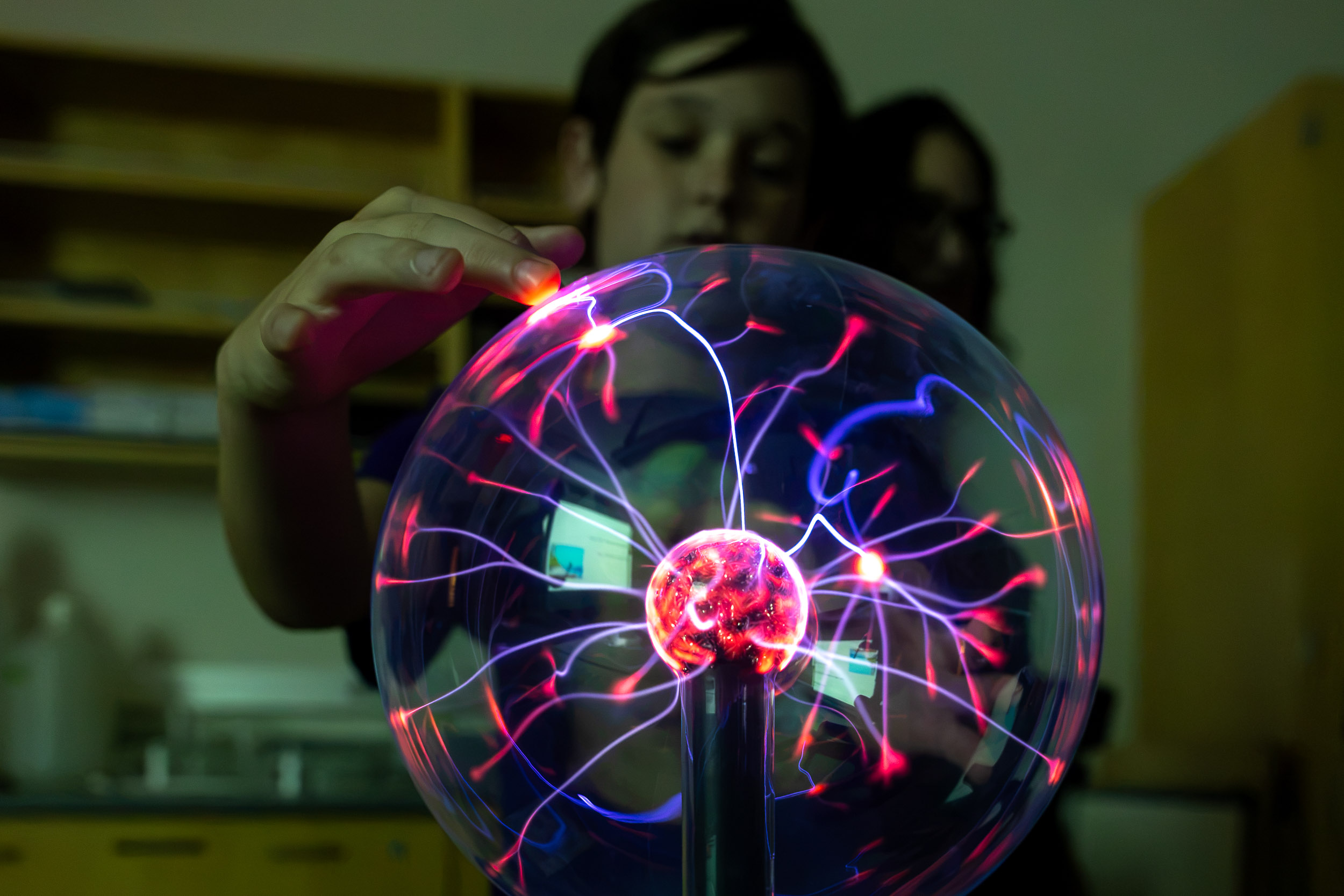 A person touches a glowing plasma ball.