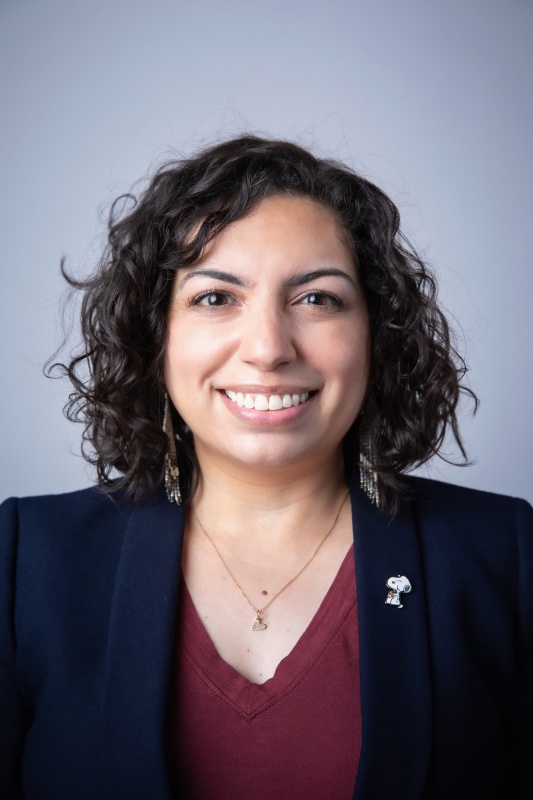 A professional photo of a woman with shoulder length curly hair, a big smile, and a fabulous personality.