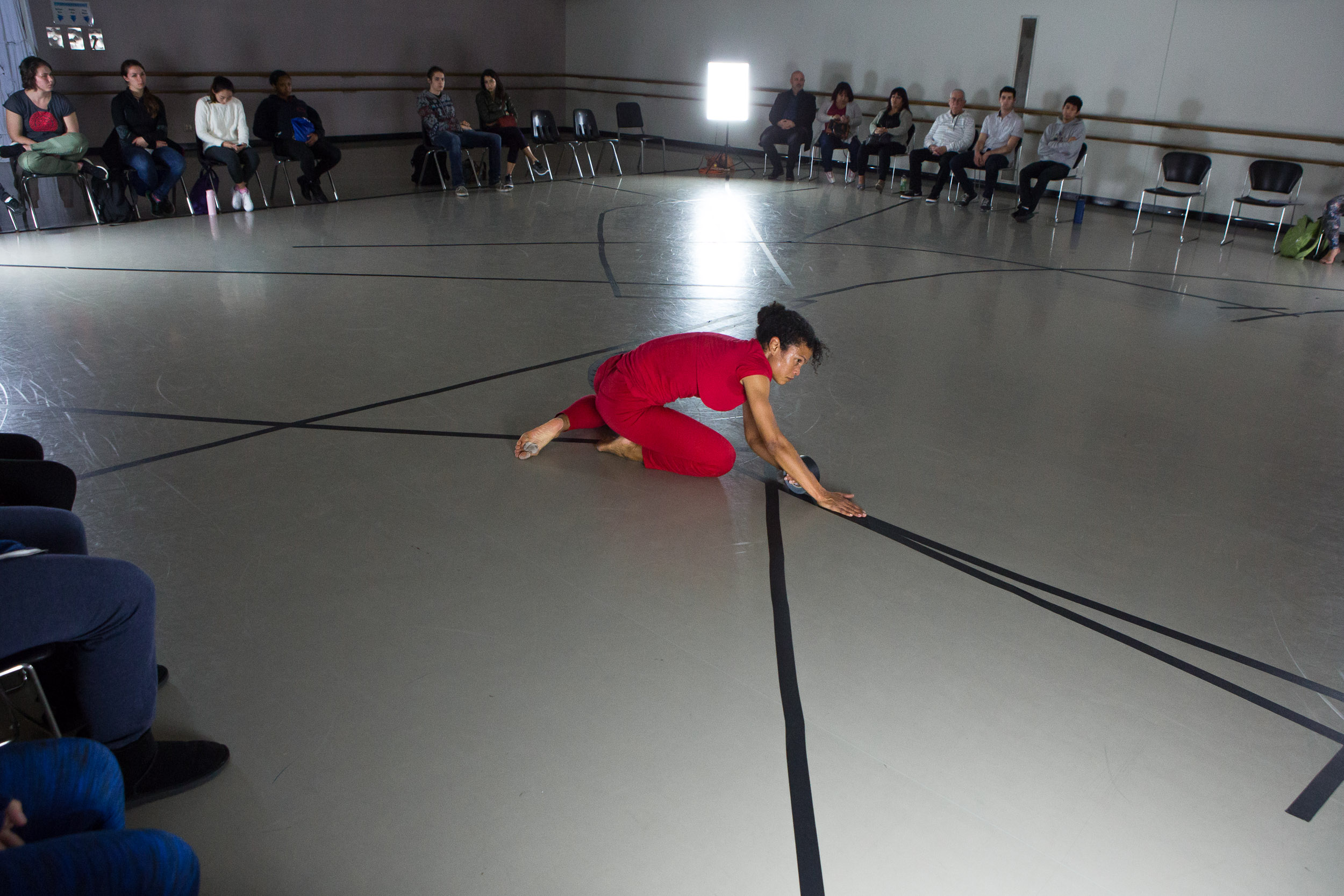 Wider view of dancer performing while dance students watch