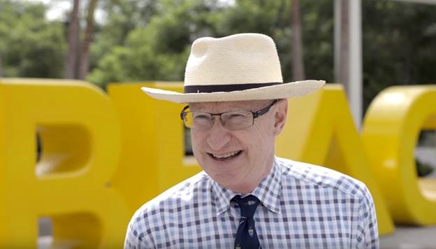 Photo of Provost, Brian Jerky, in front of Go Beach sign 