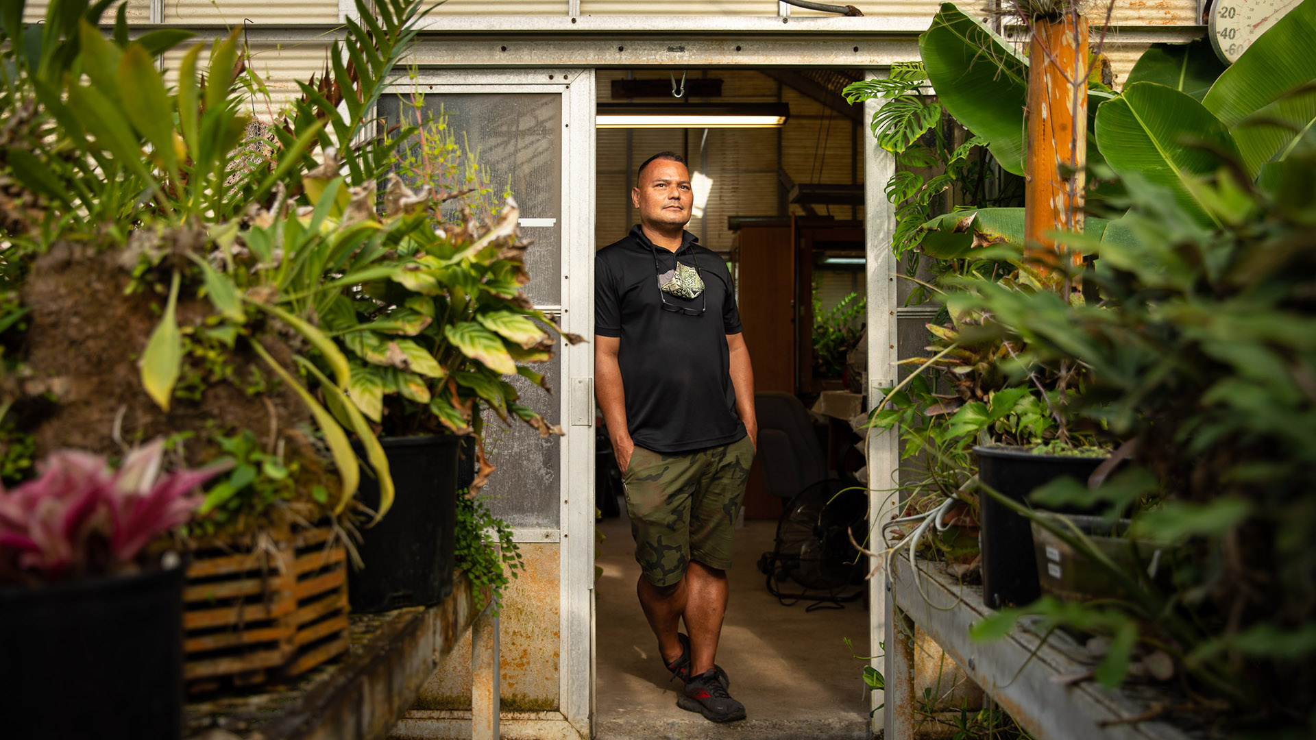 Botanist Brian Thorson standing by greenhouses