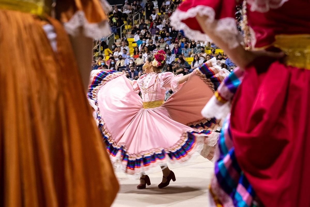 chicano-latino-07_rs.jpg A woman dances while wearing a red dress with stripes of man