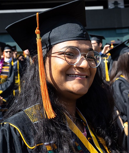 Female graduate smiles as she walks into stadium.