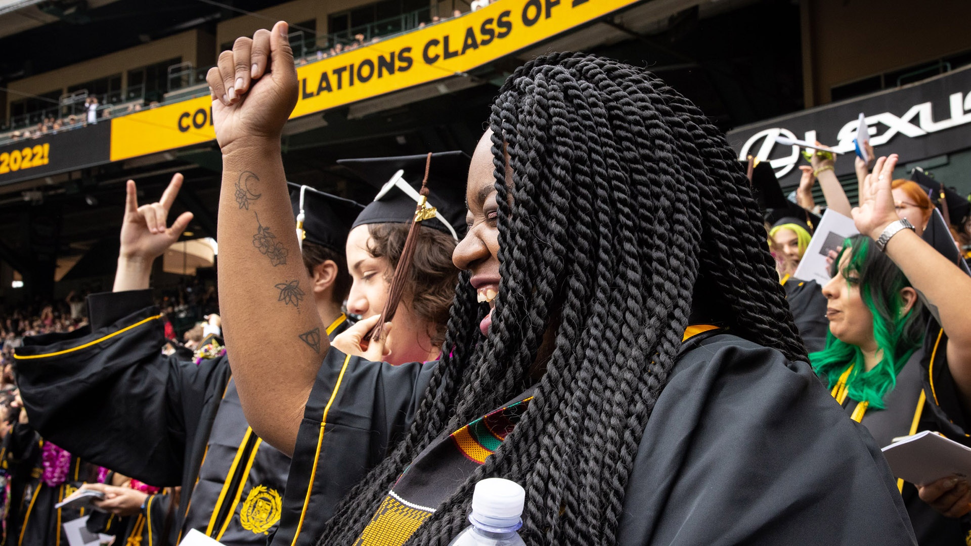 Female graduate with braids raises a celebratory fist