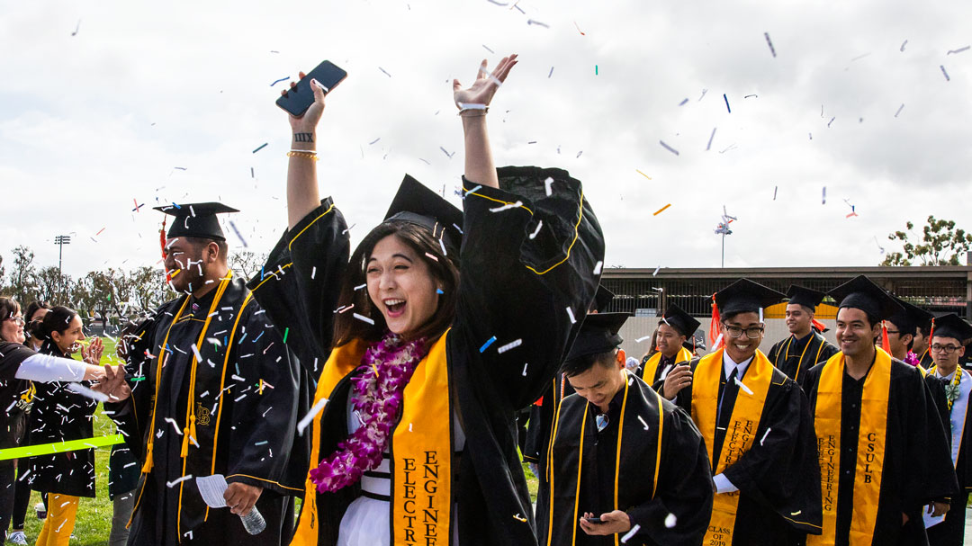 content_sc_1080_commcoe1.jpg A female graduate lifts her arms in celebration while confet