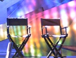 Two empty director's chairs in front of colorful background