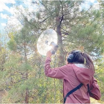 student with listening device in woods