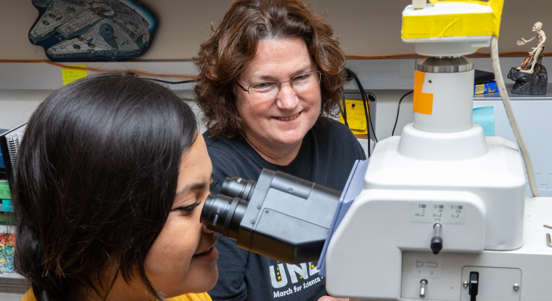 Faculty helping student at microscope