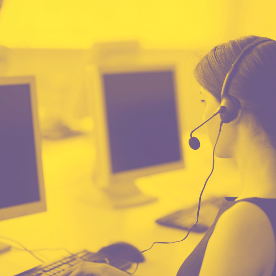 help_desk_mustard_transparent_75.png A young lady using a computer and wearing a telephone headse