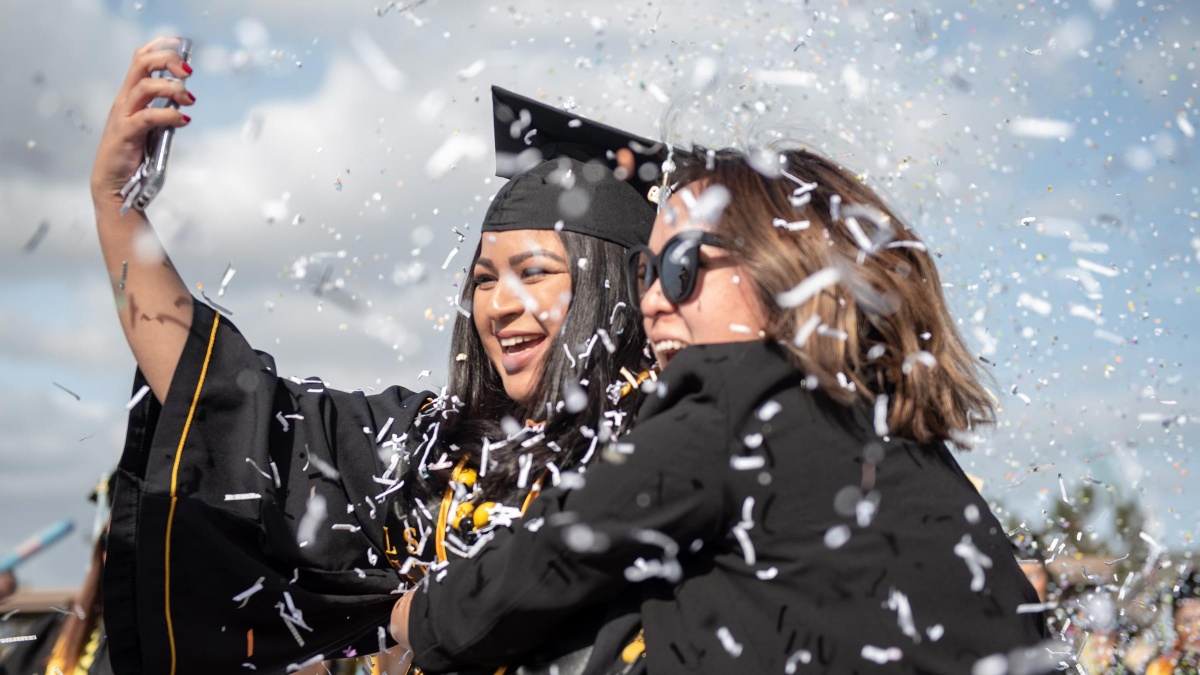 hero_comm19_ced1.jpg A smiling graduate takes a selfie with a woman while confett