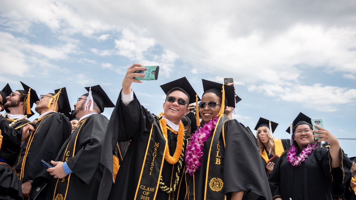 hero_comm19_cla_01.jpg Graduates taking selfies at the College of Liberal Arts cere
