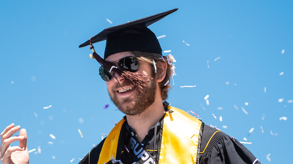 hero_comm19_cota_01.jpg A College of the Arts graduate wearing sunglasses smiles whi