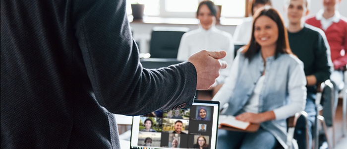 instructor in front of class and laptop with students online