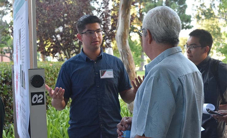 Year Two Scholar Joshuah Gagan explains his research to an a