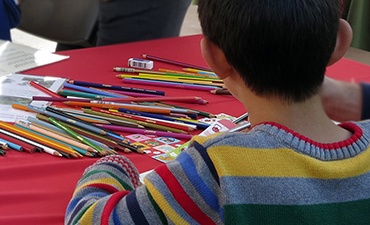Image of a child seated at a craft table with colored pencil