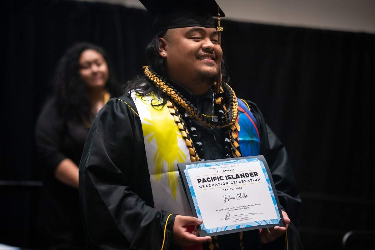 A grad receives his diploma at the  2022 Pacific Islander Cu