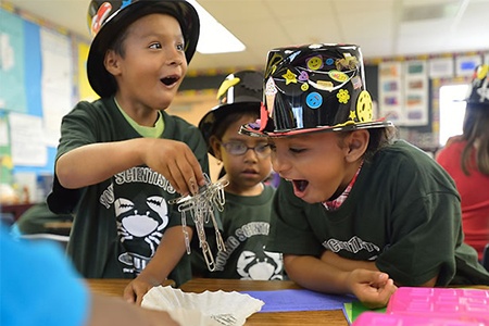 young students exploring magnetism with paper clips