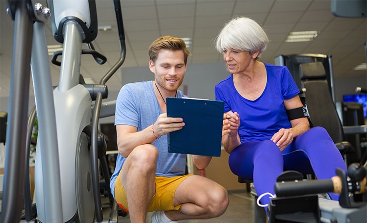 Clinical trainer with clipboard helping elderly woman