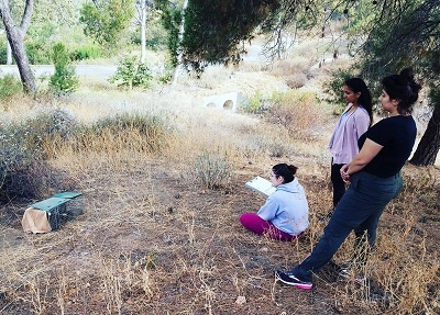 Three lab students monitor a skunk in a trap