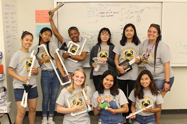 high school girls showing musical instruments they made