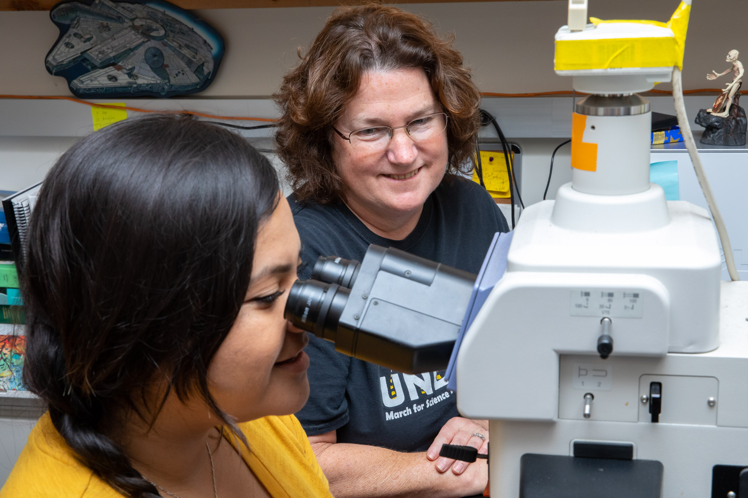 Dr. Dessie Underwood assists student looking into microscope
