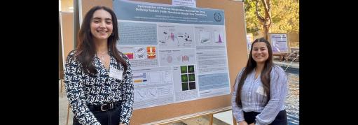two chemistry students standing proudly in front of their poster presentation