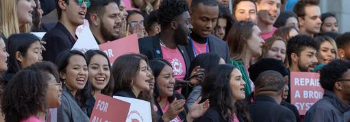Students in a large group with signs about grants