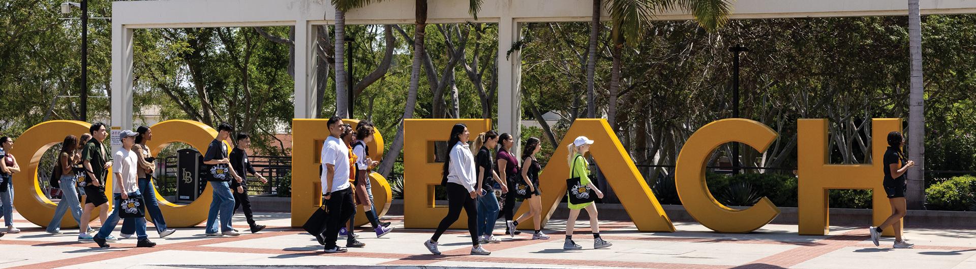 Students walking by the Go Beach letters