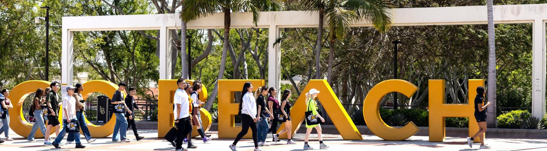 Students Walking through Go Beach sign