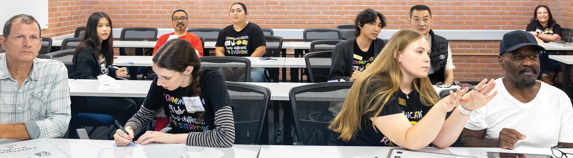 People sit at desks and focus during a classroom session