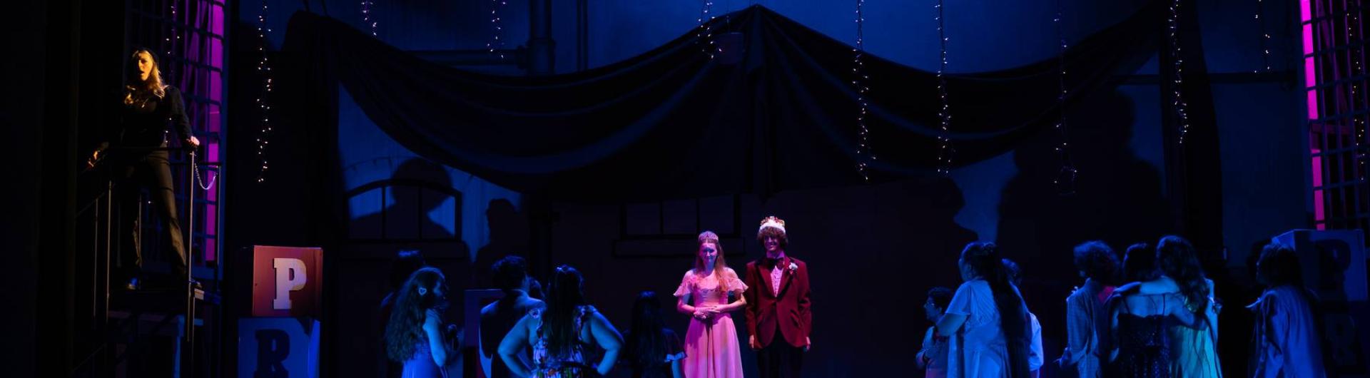 A group of high school students at prom: King and Queen are being crowned.