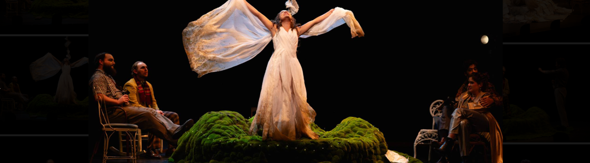 A young woman stands on a grassy mound and waves a long, sheer coat behind her.