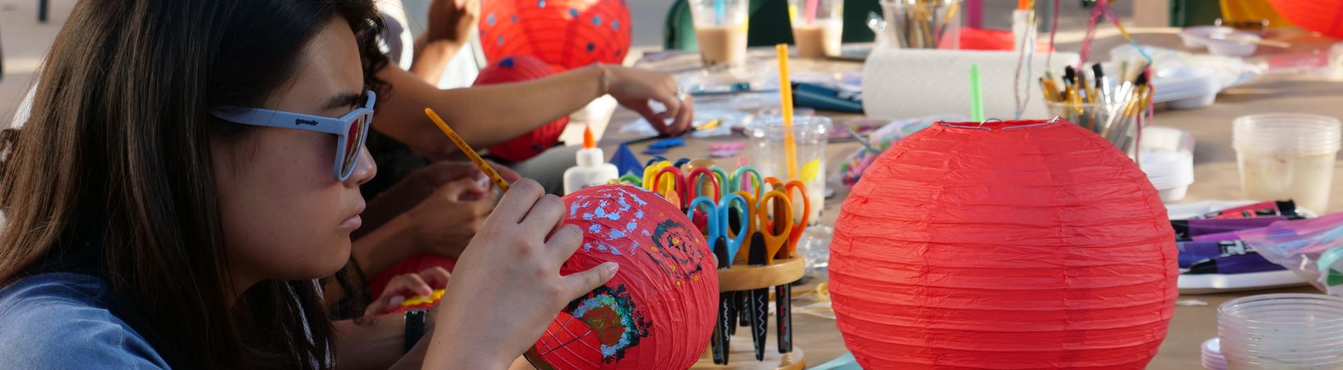 Student painting paper lanterns