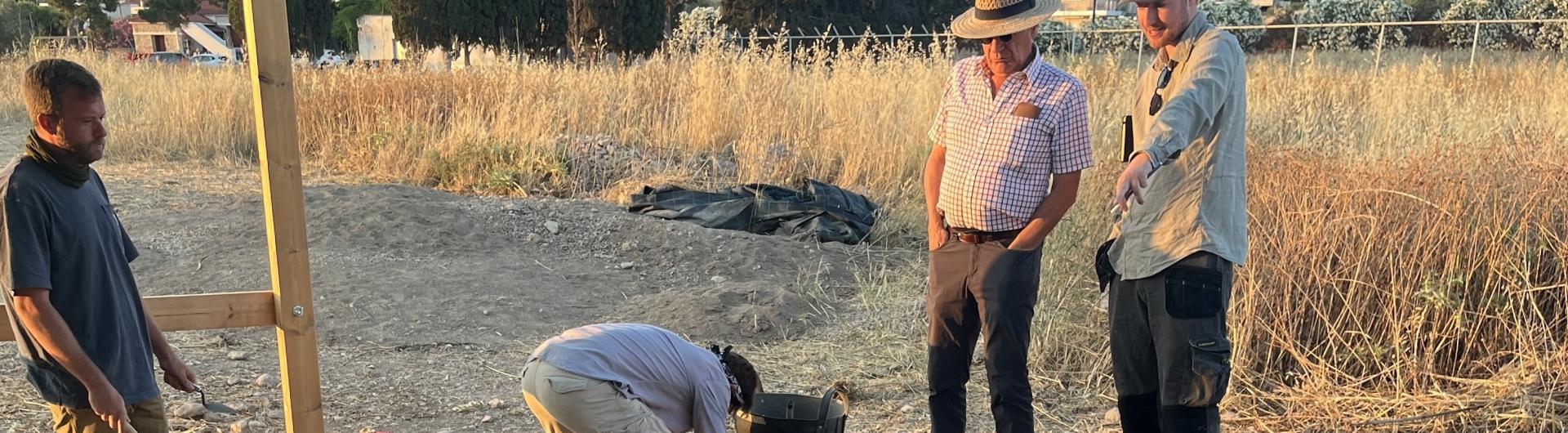 archaeologists looking at a pit in the field