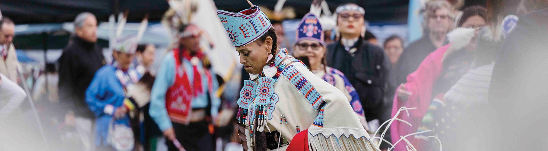 A woman wearing Indigenous regalia dancing
