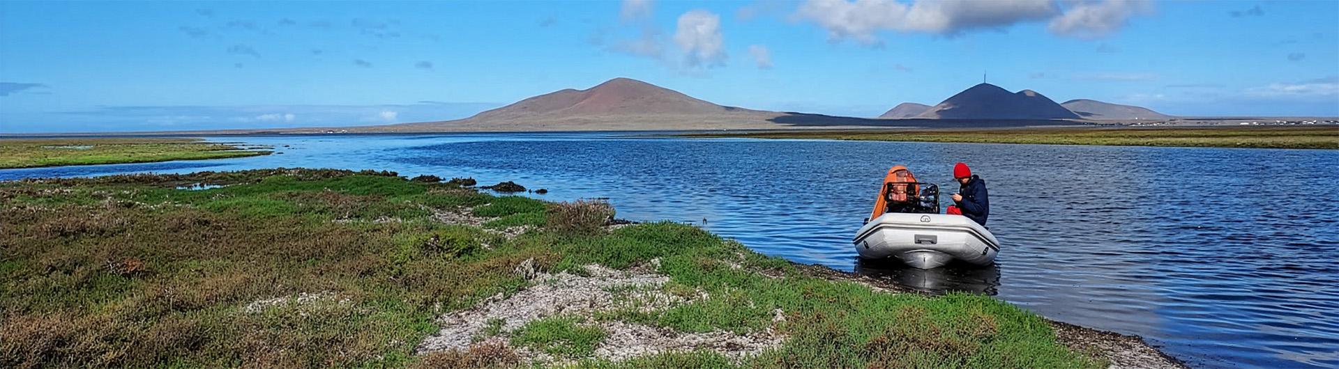 researcher reading measurements in small watercraft in Baja wetlands
