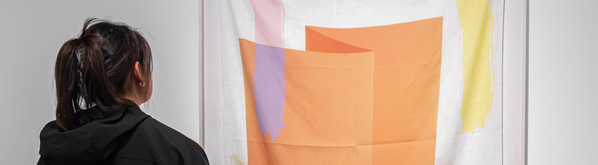 A student looking at a large art piece