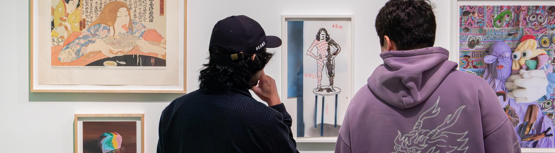 Two students viewing four pieces of artwork