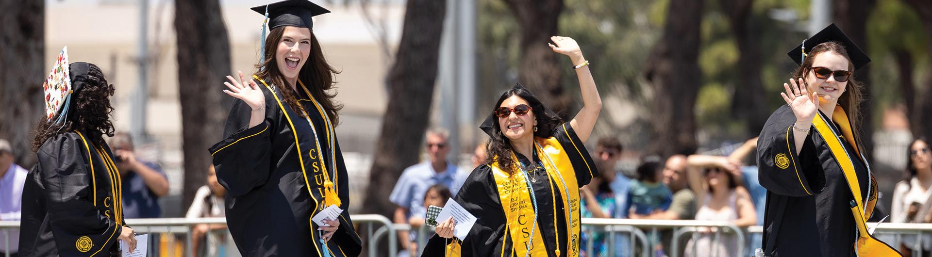 2026 CSULB graduates waving while walking in a line