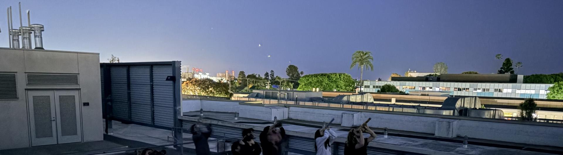 people on rooftop using telescopes to look at night sky