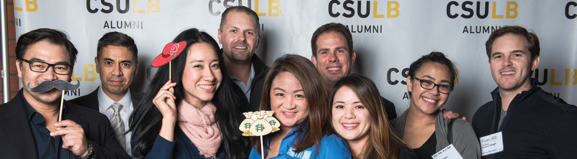 Group of MBA students posing behind a backdrop at an event